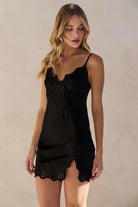 Woman wearing a black lace-trimmed nightgown against a beige background